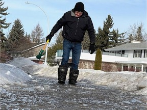 Lorne Gunter was still wading through water and melting ice on his front street on Saturday, Feb.  12, 2022, after sucking 300 gallons of water from a slough with a wet/dry vacuum.