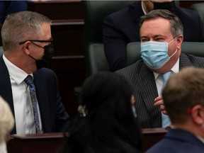 Premier Jason Kenney, right, and Finance Minister Travis Toews speak on the floor of the Alberta legislature on Thursday, Feb. 24, 2022.