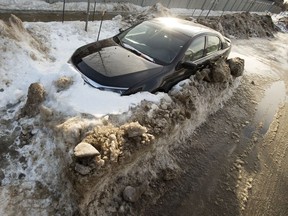 A ticketed abandoned car is partially buried by windrows along 12 Street near 37C Avenue in Edmonton on Tuesday Feb. 8, 2022.