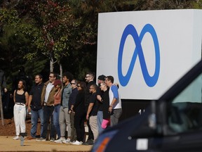 Facebook employees gather in front of a sign displaying a new logo and the name 'Meta' in front of Facebook headquarters in Menlo Park, Calif., Thursday, Oct. 28, 2021.