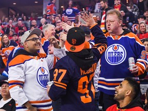 Fans of the Edmonton Oilers celebrate after Derick Brassard scored against the Calgary Flames at Scotiabank Saddledome on Saturday, March 26, 2022, in Calgary.