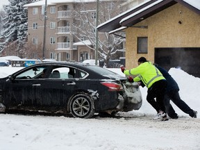 Motorists push their car out of the snow near 106 street and 87 Avenue in Edmonton, on Friday March 4, 2022.