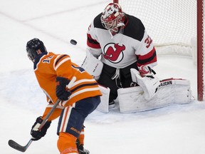 The Edmonton Oilers' Zach Hyman (18) attempts to deflect a shot past the New Jersey Devils' Jon Gillies (32) during first period NHL action at Rogers Place in Edmonton on Saturday March 19, 2022.