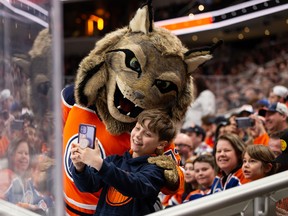 A young fan takes a selfie with Edmonton Oilers mascot Hunter during a game against the L.A. Kings at Rogers Place in Edmonton on Wednesday, March 30, 2022.