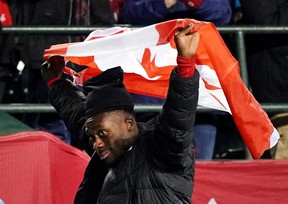 El canadiense Alphonso Davies sale del campo con la bandera canadiense sobre su cabeza después de que su equipo venciera a Costa Rica 1-0 en el partido clasificatorio para la Copa Mundial de la FIFA 2022 celebrado en el Commonwealth Stadium en Edmonton, Canadá, el viernes 12 de noviembre de 2021.