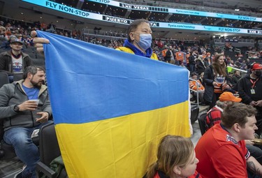 Paul Chan holds a Ukrainian flag in support of the Ukrainian people before the Edmonton Oilers play the Washington Capitals on Wednesday, March 9, 2022 in Edmonton.