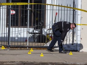 An Edmonton Police Service member investigates the scene of a fatal shooting outside a 118 Avenue lounge, March 12, 2022.