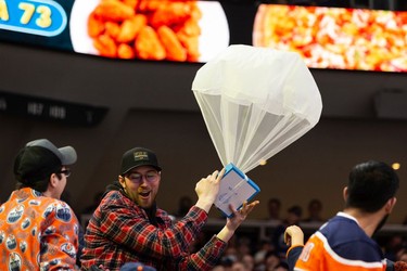 A fan catches some free pizza during a contest as the Edmonton Oilers play the San Jose Sharks during first period NHL action at Rogers Place in Edmonton, on Thursday, March 24, 2022.