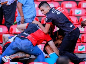 People are beaten in the seating area of Corregidora Stadium, leaving at least 22 injured in a brawl when soccer fans stormed the field during a top-flight match between mid-table Queretaro and last year's Liga MX champions Atlas, in Queretaro, Mexico, Saturday, March 5, 2022.