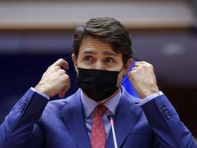 Prime Minister Justin Trudeau removes his face mask to address European lawmakers amid Russia's invasion of Ukraine, in Brussels, Belgium, March 23, 2022.
