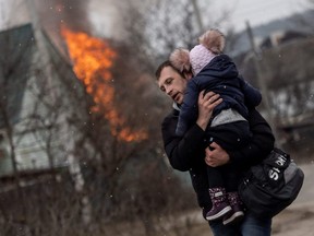 A man and a child escape from the town of Irpin, after heavy shelling on the only escape route used by locals, while Russian troops advance towards the capital Kyiv, Ukraine, Sunday, March 6, 2022.