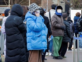 People wait in line to undergo the coronavirus disease (COVID-19) test at a testing site which is temporarily set up at a public health center in Seoul, South Korea, February 24, 2022.