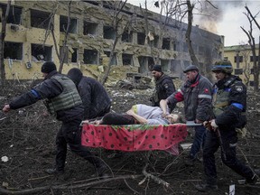 Ukrainian emergency employees and volunteers carry an injured pregnant woman from the damaged by shelling maternity hospital in Mariupol, Ukraine, Wednesday, March 9, 2022.