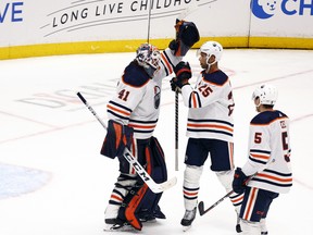 Mike Smith (41), Darnell Nurse (25) and Cody Ceci (5) of the Edmonton Oilers celebrate a 6-1 win against the Anaheim Ducks at Honda Center on Sunday, April 03, 2022, in Anaheim, Calif.