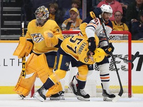 Dante Fabbro #57 of the Nashville Predators and Evander Kane #91 of the Edmonton Oilers hold each other near Juuse Saros #74 of the Nashville Predators in the net at Bridgestone Arena on April 14, 2022, in Nashville, Tennessee.