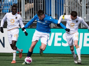 FC Edmonton striker Tobias Warschewski (10) battles Valour FC midfielders Daryl Fordyce (16) and William Akio (19) during second half Canadian Premier League soccer action at Clarke Stadium in Edmonton, on Sunday, April 10, 2022.