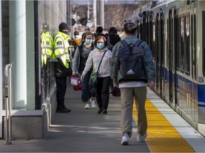 A security guard stands on duty as passengers make their way through the Health Sciences/Jubilee LRT station on April 28, 2022 in Edmonton.