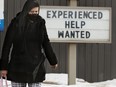 A woman passes a help wanted sign at a Jiffy Lube location in Edmonton on March 15, 2022.