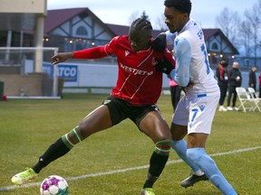 Cavalry FC's Jean-Aniel Assi takes the ball to the corner in front of Edmonton FC's Courtney Jr Mitchell-Smith during a Canadian Championship match at ATCO Field at Spruce Meadows in Calgary on Tuesday, May 10, 2022.