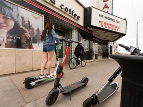 An e-scooter rider and a cyclist travel on the sidewalk along 109 Street at 87 Avenue in May 2021.