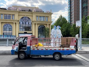 Workers in protective suits stand in a truck on a street during the Labour Day holiday, in Chaoyang district of Beijing, China May 1, 2022.
