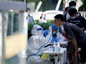 A health worker takes a swab sample from a man to be tested for COVID-19 at a swab collection site in Beijing, Monday, May 23, 2022.