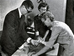 Cam's mother, Thelma, manipulates his head as volunteers Audrey Helgason and John Casey move his limbs in 1964.