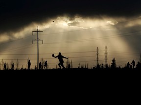 People play softball at Meadows District Park, Silver Berry Rd NW, as rain clouds gather in the background, in Edmonton Monday May 16, 2022.