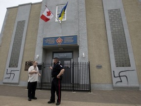 A police office speaks with Marco Levytsky, with the Ukrainian National Federation of Canada in Edmonton, after the federation's building was spray painted with swastikas, Friday May 13, 2022. Photo By David Bloom
