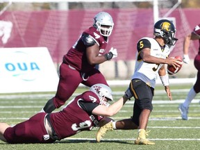Waterloo Warriors quarterback Tre Ford evades Ottawa Gee-Gees defenders during an Ontario University Athletics football quarterfinal playoff game at uOttawa on Saturday, Oct. 26, 2019.