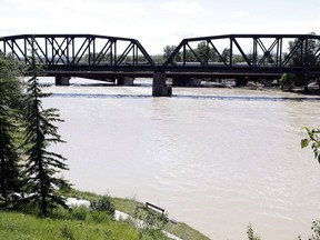 Crews work to stabilize a Canadian Pacific freight train as is sits derailed on a failing bridge over the flooded Bow River in Calgary on Thursday, June 27, 2013.
