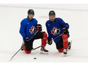 Xavier Bourgault (left) and Connor Bedard take a knee during a Team Canada practice ahead of the 2022 IIHF World Junior Championship at the Downtown Community Arena at Rogers Place in Edmonton, on Wednesday, Dec. 22, 2021.