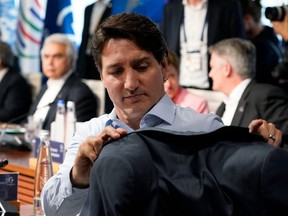 Prime Minister Justin Trudeau hangs his coat on the back of his chair as he waits for the start of the fifth working session with representatives of Seven rich nations (G7) and Outreach guests about "Investing in a better future: Climate, Energy, Health" on June 27, 2022 at Elmau Castle, southern Germany, during the G7 Summit.