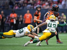 B.C. Lions running back James Butler (24) avoids tackles by Edmonton Elks linebackers Adam Konar, left, and Enock Makonzo (43) on the way to his second of four touchdowns in Vancouver on Saturday, June 11, 2022.