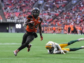 B.C. Lions running back James Butler, left, gets away from a tackle by the Edmonton Elks' Trey Hoskins and runs the ball in for his first touchdown in Vancouver on June 11, 2022.