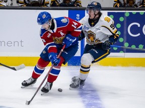 Josh Williams (14) of the Edmonton Oil Kings battle for position with Pierrick Dubé (92) of the Shawinigan Cataractes at the 2022 Memorial Cup on June 21, 2022,  at the Harbour Station arena in Saint John, NB.