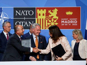 Turkish Foreign Minister Mevlut Cavusoglu shakes hands with Sweden's Foreign Minister Ann Linde next to Finnish Foreign Minister Pekka Haavisto , Sweden's Prime Minister Magdalena Andersson and NATO Secretary General Jens Stoltenberg after signing a document during a NATO summit in Madrid, Spain, June 28, 2022.
