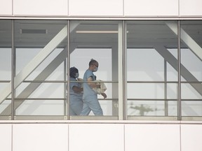 Health-care workers walk across a sky bridge at a hospital in Montreal, Sunday, February 6, 2022, as the COVID-19 pandemic continues in Canada.