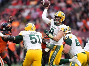 Edmonton Elks quarterback Nick Arbuckle (9) passes as Antonio Garcia (51) holds off B.C. Lions' Obum Gwacham (98) during the first half of CFL football game in Vancouver, on Saturday, June 11, 2022.