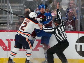Edmonton Oilers defenseman Duncan Keith (2) and Colorado Avalanche right wing Logan O'Connor (25) battle for the puck in front of linesman Steve Barton (59) in the first period of game two of the Western Conference Final of the 2022 Stanley Cup Playoffs at Ball Arena.
