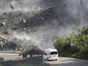 Boulders fall as a vehicle negotiates a road during an earthquake in Bauko, Mountain Province, Philippines on Wednesday July 27, 2022. A strong earthquake left some people dead and injured dozens in the northern Philippines on Wednesday, where the temblor set off small landslides and damaged buildings and churches and prompted terrified crowds and hospital patients in the capital to rush outdoors. One passenger was injured after a boulder hit the vehicle.