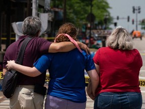 A family embraces while observing the scene of a mass shooting at a July 4th Parade in downtown Highland Park, Ill., Tuesday, July 5, 2022.