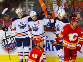 Edmonton Oilers Xavier Bourgault, left, celebrates with teammate Derek Ryan, middle, a goal against the Calgary Flames during pre-season NHL hockey in Calgary on Sunday, September 26, 2021.