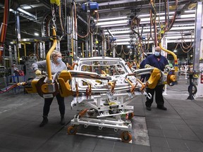 GM workers use human assistance automation to weld vehicle doors at the General Motors assembly plant during the COVID-19 pandemic in Oshawa, Ont., on Friday, March 19, 2021.