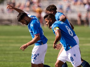 FC Edmonton's Wesley Timoteo (22) celebrates Azriel Gonzalez's goal with teammates on Halifax Wanderers' goalkeeper Kieran Baskett during a Canadian Premier League soccer game at Clarke Stadium in Edmonton on Sunday, Aug. 28, 2022.