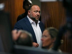 Alex Jones walks into the courtroom in front of Scarlett Lewis and Neil Heslin, the parents of 6-year-old Sand Hook shooting victim Jesse Lewis, at the Travis County Courthouse in Austin, Texas, July 28, 2022.