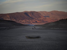 A formerly sunken boat sits on cracked earth hundreds of feet from what is now the shoreline on Lake Mead at the Lake Mead National Recreation Area, May 9, 2022, near Boulder City, Nev.
