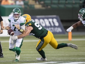 Saskatchewan Roughriders quarterback Cody Fajardo (7) fumbles the ball under pressure from Edmonton Elks defensive tackle Jake Ceresna (94) in Edmonton on Aug. 13, 2022.