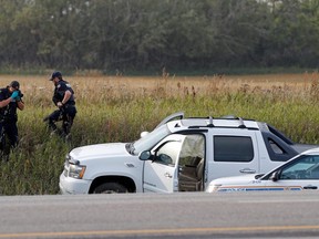 A RCMP officer takes a pictures of police vehicles next to a pickup truck at the scene where suspect Myles Sanderson was arrested, along Highway 11 near the town of Rosthern, Saskt, on Thursday, Sept. 7, 2022.