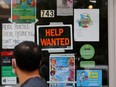 A pedestrian passes a "Help Wanted" sign in the door of a hardware store. REUTERS/Brian Snyder